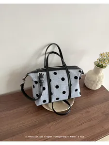 Elegante bolso tote de lona con lunares estilo vintage y correas de cuero negro sobre madera
