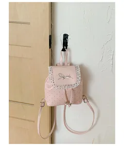 Sweet pink mini backpack with lace trim and bow detail hanging on a white wall