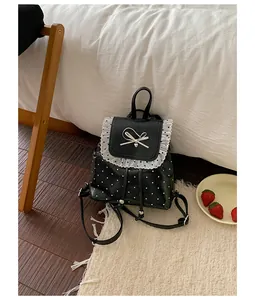 Black polka dot backpack with white lace ruffles and a bow in a cozy bedroom scene