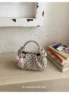 Stylish beige polka dot handbag featuring an elegant pearl and pink bow decorative charm