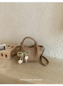 Nahaufnahme einer strukturierten khakifarbenen Eimertasche mit Perlenbogenschmuck