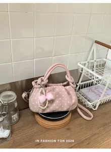 Detailed view of pink polka dot handbag with elegant pearl bow charm