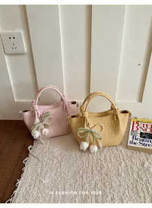Elegante Mini-Lederhandtaschen in Rosa und Gelb mit stilvollen Perlen-Blumenanhängern.