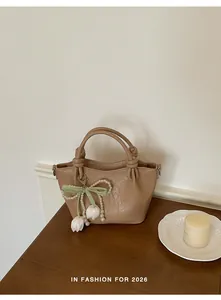 Detailansicht beige Handtasche mit eleganter Perlen-Schleife und Blumen-Anhänger
