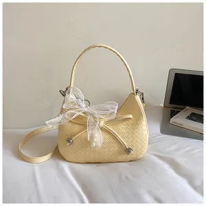 Detailed macro view of cream woven handbag featuring a delicate lace bow and pearl charms