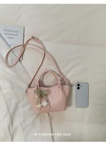 Detailansicht einer rosa Leder-Eimertasche mit Perlenanhänger und grüner Schleifendekoration