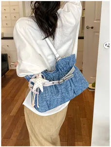 Moderna borsa tote blu plissettata in denim con ciondolo a stella portata a spalla
