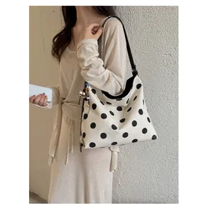 Bolso tote de lona con lunares de gran capacidad sobre el hombro de una modelo para estilo casual.