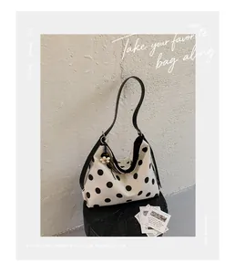 Vista detallada de un gran bolso tote de lona con lunares y un colgante de flores