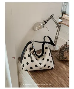 Vista detallada de la bolsa tote de lona con lunares grandes y correas de hombro negras