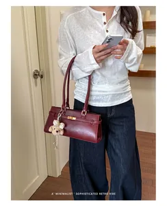 Model carrying a burgundy minimalist retro underarm tote bag with teddy bear charm