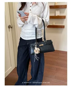 Minimalist black faux leather underarm tote bag worn by a model in a casual setting