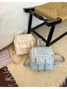 Zwei Vintage-Mini-Rucksäcke mit Spitzenbesatz und Perlenherz-Details auf einem Teppich