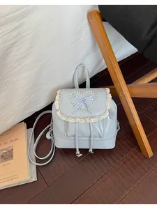 Nahaufnahme eines blauen Vintage-Minirucksacks mit Spitzenbesatz und Perlenherz.