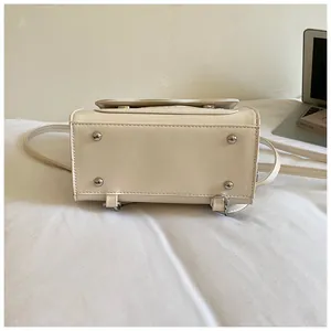 Détail du dessous d'un sac à dos léger pour femme en crème avec des clous métalliques