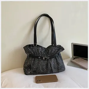 Vista dettagliata della borsa tote plissettata scura con cinturino decorativo in pelle.