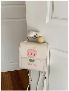 Détail d'un mini sac à dos beige avec une broderie tulipe et poignée à nœud.