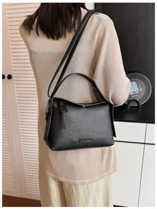 Elegant black lychee pattern leather crossbody bag shown on model in modern home setting