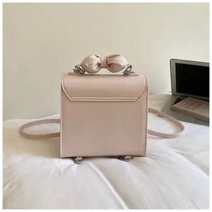 Vue arrière détaillée d'un sac à dos rose élégant avec une poignée décorative en nœud