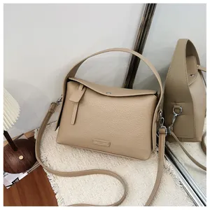 Detailed view of a beige litchi texture square handbag with a sturdy top handle.