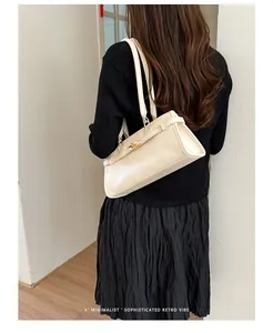 Elegant off-white minimalist shoulder bag carried by a model in a modern indoor setting