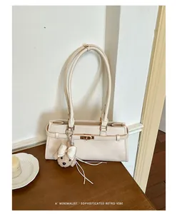 Close-up of minimalist cream underarm tote bag with cute plush teddy bear charm