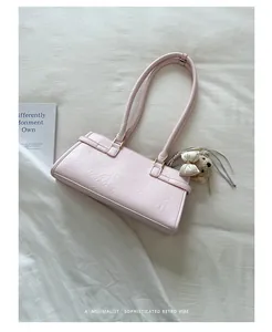 Close-up of a pink minimalist underarm bag featuring a cute plush bear charm decoration