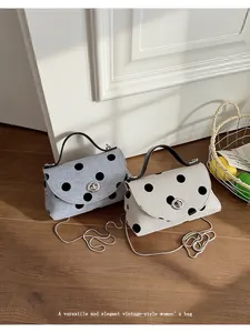 Close-up van vintage crossbodytassen met polkadots, metalen kettingen en draaisluiting.