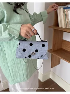 Lifestyle-weergave van een lichtblauwe vintage crossbodytas met stippen en ketting
