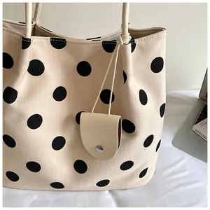 Detalle de bolso tote de lona beige con lunares negros y accesorio de estuche colgante