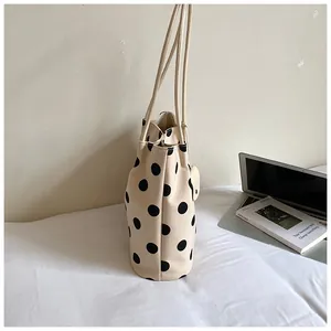 Vista lateral detallada de un elegante bolso tote con lunares crema para la oficina