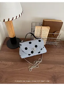 Detailopname van een vintage mini-tas met stippen en kettingriem op een houten tafel.