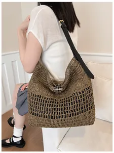 Détail d'un grand sac de plage en paille tressée avec bandoulière noire en cuir