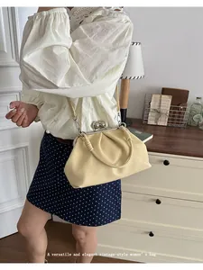 Elegant cream pleated crossbody bag with kiss-lock clasp in a vintage lifestyle setting.