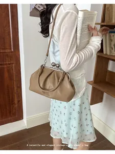 Vintage khaki pleated shell bag shown on shoulder in a cozy library setting