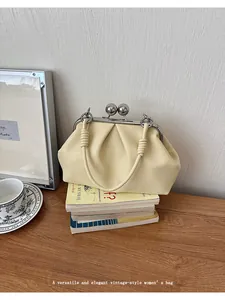 Detailed shot of the cream pleated shell handbag on a vintage book stack