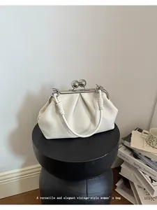 Elegant white pleated handbag with vintage kiss-lock on a minimalist black stool pedestal.
