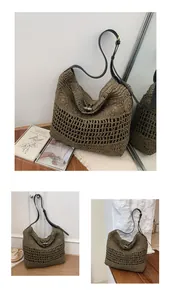 Grand sac en paille ajouré avec bandoulière noire et fermoir à bascule en détail.