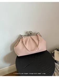 Elegant light pink pleated shell bag for women displayed on a black wooden stand.