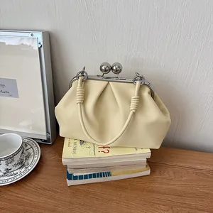 Close-up of a stylish creamy yellow pleated handbag with an elegant silver clasp closure
