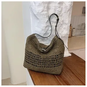 Vue détaillée du sac de plage en paille tissée avec texture ajourée et bandoulière noire