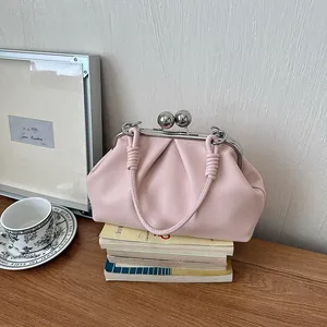 Elegant pink pleated kiss-lock handbag placed on vintage books in a lifestyle setting