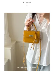 Primo piano di una borsa a mano vintage in pelle gialla tenuta da una modella in camicia.