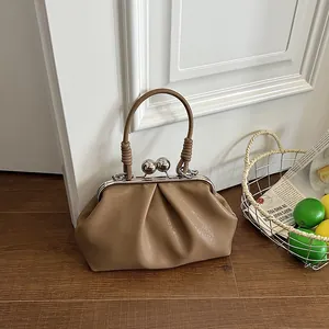 Detail shot of a khaki pleated handbag with vintage metal kiss-lock and round handle