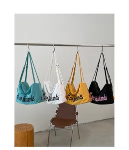 Four colorful lightweight nylon tote bags hanging on a rack in a minimalist studio setting