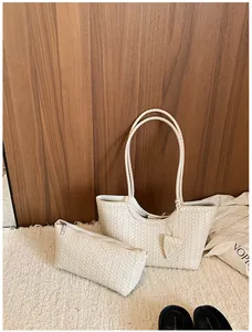 Set of cream woven tote bag and matching pouch on a neutral textured background