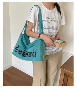 Model carrying a stylish teal nylon tote bag featuring 'off on weekends' text print.