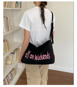 Back view of female model wearing a black nylon crossbody bag with pink embroidery