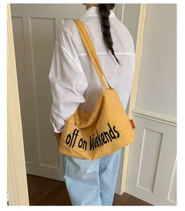 Lifestyle view of a casual large-capacity yellow nylon shoulder bag with slogan print