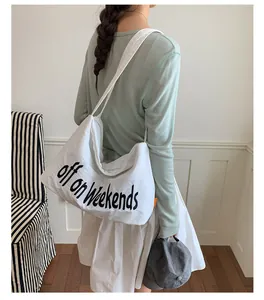 Close-up view of a casual white nylon tote bag featuring black slogan text print